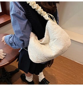 Detailed side view of white quilted hobo bag with trendy ruched shoulder strap design
