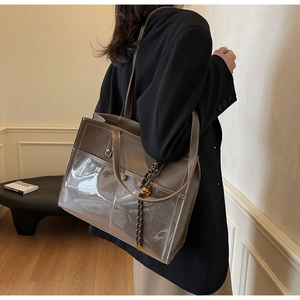 Macro detail of brown tote bag featuring PVC stitching and metal bell charm accent