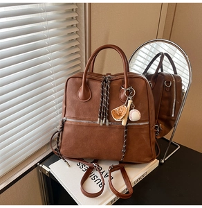 Dettaglio dello zaino vintage in pelle PU marrone con ciondoli da baseball e tiranti
