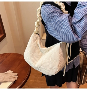 Detail of quilted puffy tote bag with ruffled shoulder strap in off-white nylon fabric