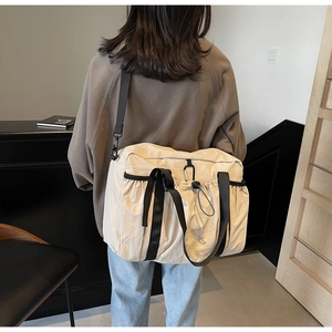 Detailed back view of a beige canvas bucket bag with black straps on a female model