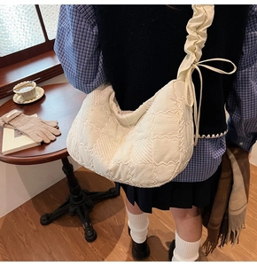 Detail of an ivory pleated nylon tote bag with quilted pattern and ribbon bow on a strap