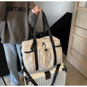 Beige nylon tote bag shown mounted on a suitcase handle for easy travel commute