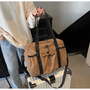 Detail of khaki nylon tote bag on a suitcase showing drawstrings and shoulder strap