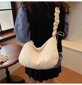 Detail of cream quilted tote bag featuring textured checkerboard fabric and bow shoulder strap