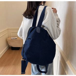 Detail of navy denim backpack showing reinforced leather-look shoulder strap attachment