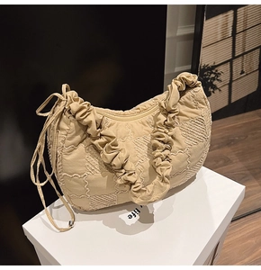 Detail of beige quilted fabric hobo bag with ruched handle and side drawstring decoration