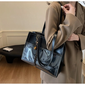 Detail of black tote bag featuring clear PVC panels and white contrast stitching