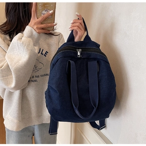 Detail showing the heavy-duty denim fabric texture and silver zippers on a casual backpack
