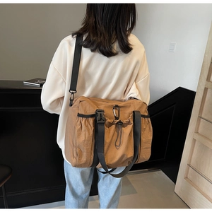 Detail view of khaki nylon tote bag showing drawstrings and plastic buckle closure