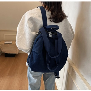 Detail of deep blue denim backpack showing dual metal zippers and durable canvas texture