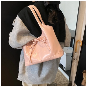 Macro view of glossy pink leather shoulder bag featuring bow knot and embossed text detail