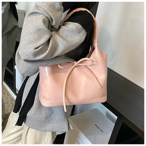 Detailed view of the oversized pink shoulder bag featuring a large leather bow decoration