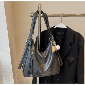Close-up of charcoal hobo bag with zipper tassels and baseball charms on suit hanger