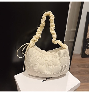 Detail of quilted texture fabric and pleated handle on the creamy white tote bag