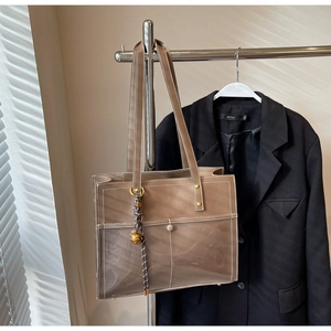 Close-up of brown tote bag with white contrast stitching and decorative outer pockets