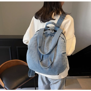 Rear view of a large denim backpack with wide straps worn by a model in casual wear