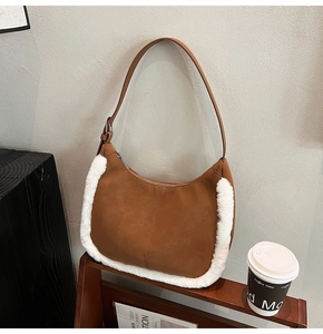 Detail of hobo bag featuring brown matte suede and white faux fur trim on a wooden stand