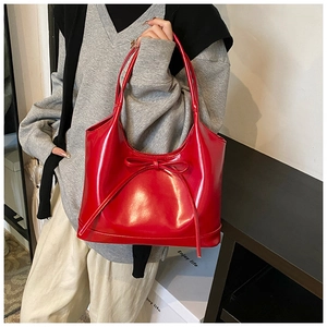 Detail of red patent leather shoulder bag with a bow tie decoration and mirror finish