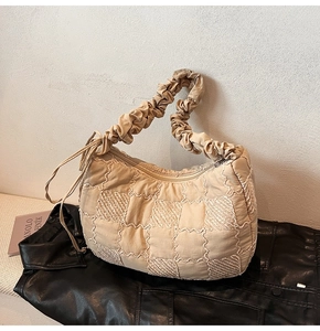 Close-up of pleated handle and quilted checkerboard texture on beige nylon tote bag