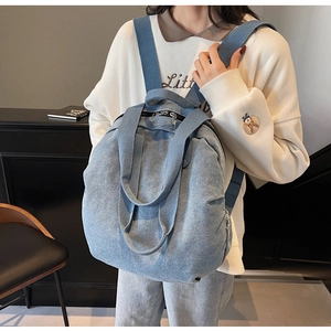 Detail of light blue denim backpack with silver double zippers and sturdy top handle