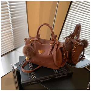 Detail of vintage brown textured leather handbag with gold zipper and fur ball charm