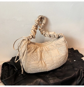 Detail of beige quilted nylon tote bag with pleated handle and drawstring design