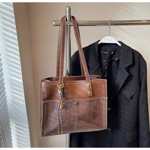 Detail of brown PU leather tote bag with white stitching and decorative metal ball