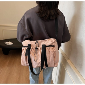 Pink pleated nylon tote bag with wide black strap and silver climbing hook detail