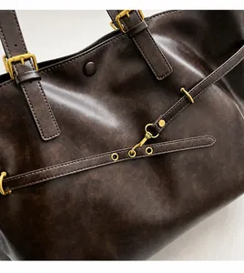 Close-up of vintage brown leather tote bag showing gold buckles and fine stitching