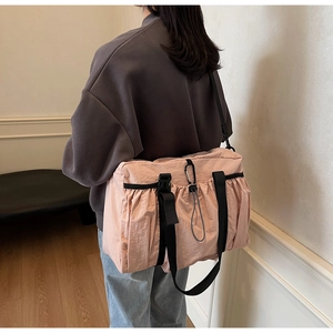 Detailed back view of pink nylon tote bag with drawstring texture and black straps