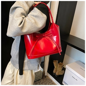 Detail of red leather tote bag with glossy finish and delicate bow tie decoration