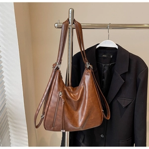 Detail view of brown vintage PU leather tote bag with stylish vertical zipper and fringe