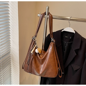 Detail of brown vintage tote bag with PU leather texture and metal pendant accents