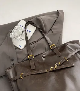 Detail of dark brown vintage faux leather tote with golden metallic buckles and straps