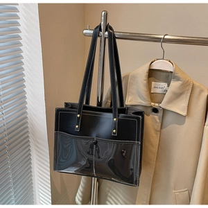 Detail of black leather and transparent PVC tote bag with white stitching on a hanger