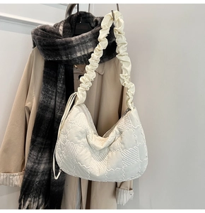 Close-up of quilted cream tote bag with ruched shoulder strap and zipper detail