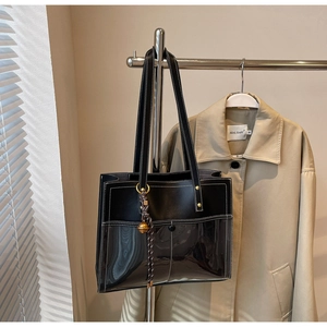 Close-up of a contrast tote bag with black leather stitching and decorative charm
