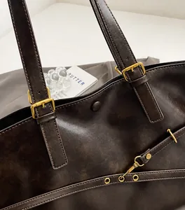 Detailed close-up of dark brown leather tote bag with vintage gold hardware and adjustable strap