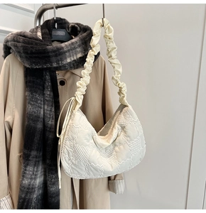 Detail view of cream quilted tote bag featuring scrunchie shoulder strap and nylon fabric