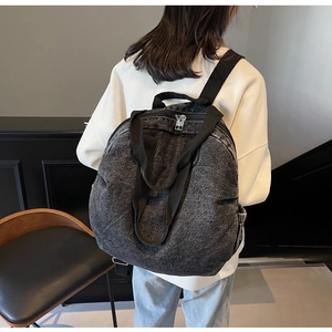 Detail view of large denim backpack showing weathered texture and dual carry handles
