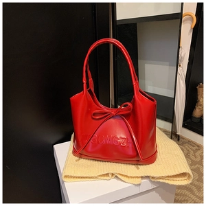Detailed close-up of a vibrant red handbag with a large bow and embossed GONGZHU texture