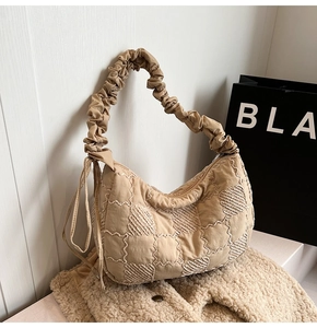 Detail of beige nylon tote featuring wavy quilting and pleated ruched handle texture