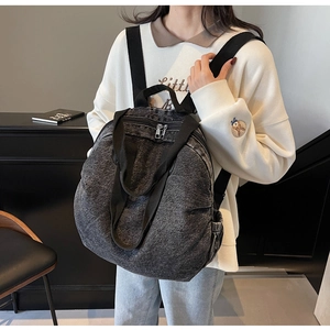 Detail view of washed denim backpack with silver zipper and side elastic pocket