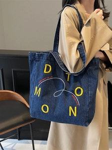 Deep blue denim tote bag with yellow embroidery text and sturdy shoulder straps
