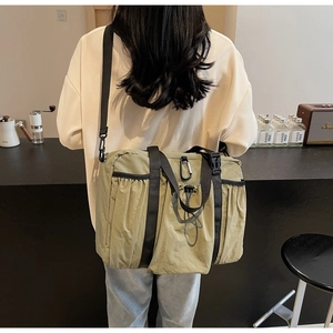 Detailed view of the olive green nylon tote bag with wide black shoulder straps and drawstring