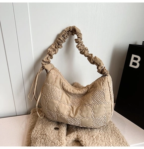 Detail of beige pleated scrunchie strap and quilted fabric texture on the tote bag