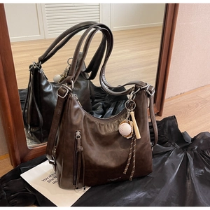 Detail of dark brown leather tote bag with vintage texture and baseball charm