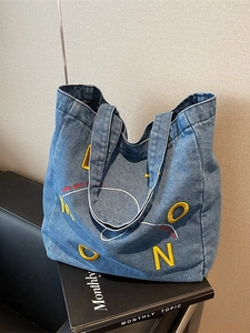 Blue denim tote bag with Moon embroidery on a leather sofa, casual large capacity style