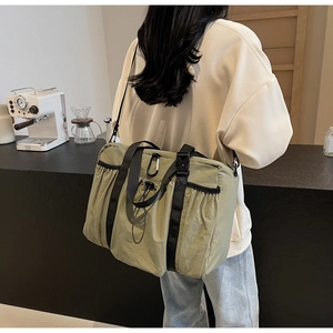 Outdoor style olive green nylon bucket bag with drawstring pocket and wide shoulder strap